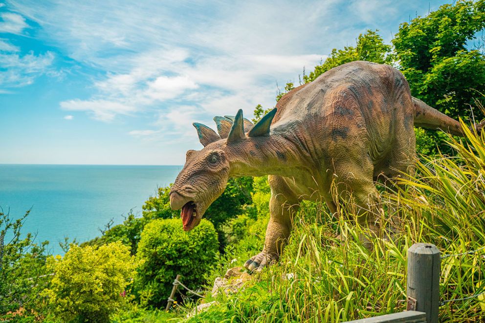 A dinosaur overlooking a calm blue sea